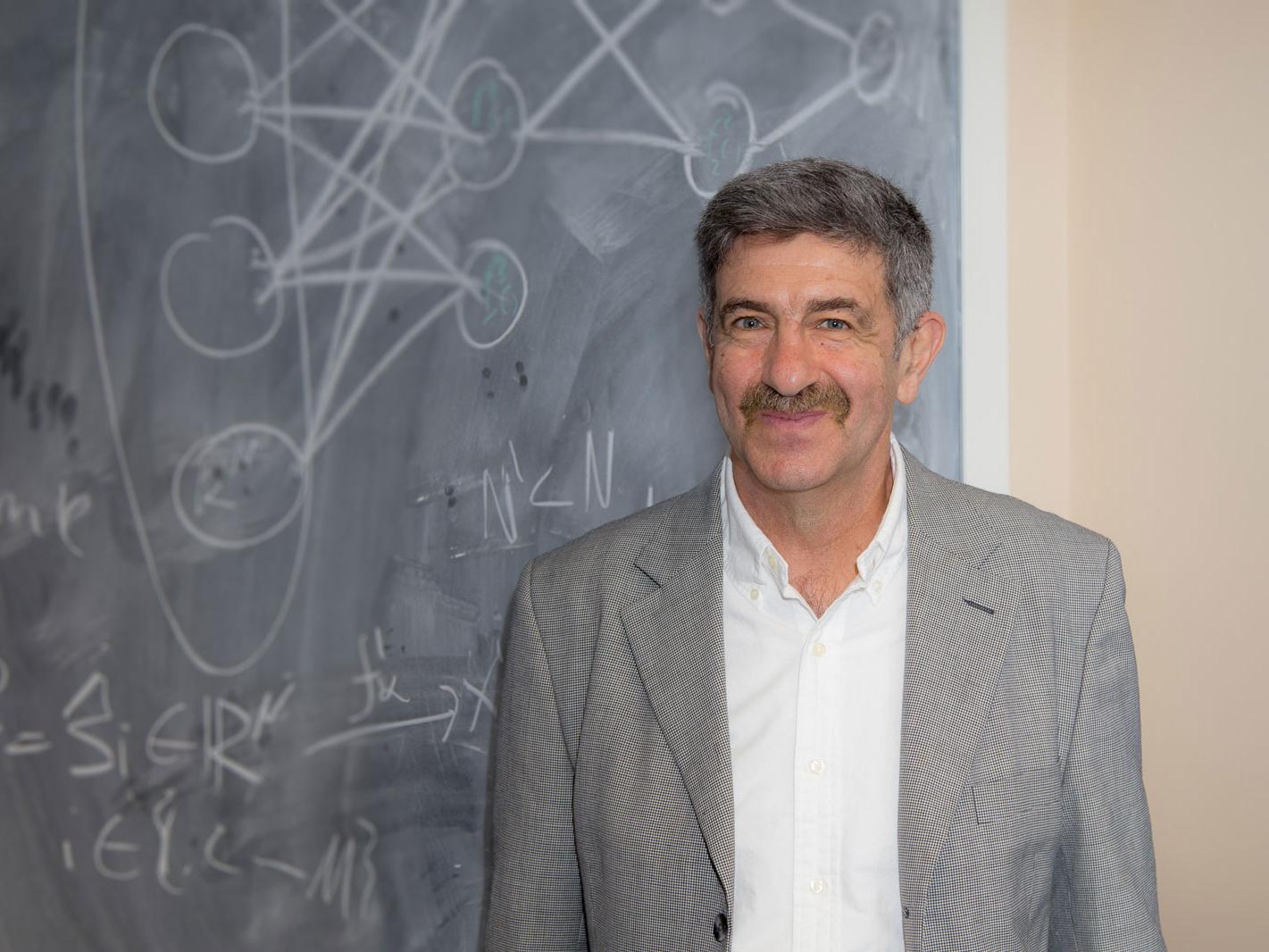 Berlyand stands in front of chalkboard