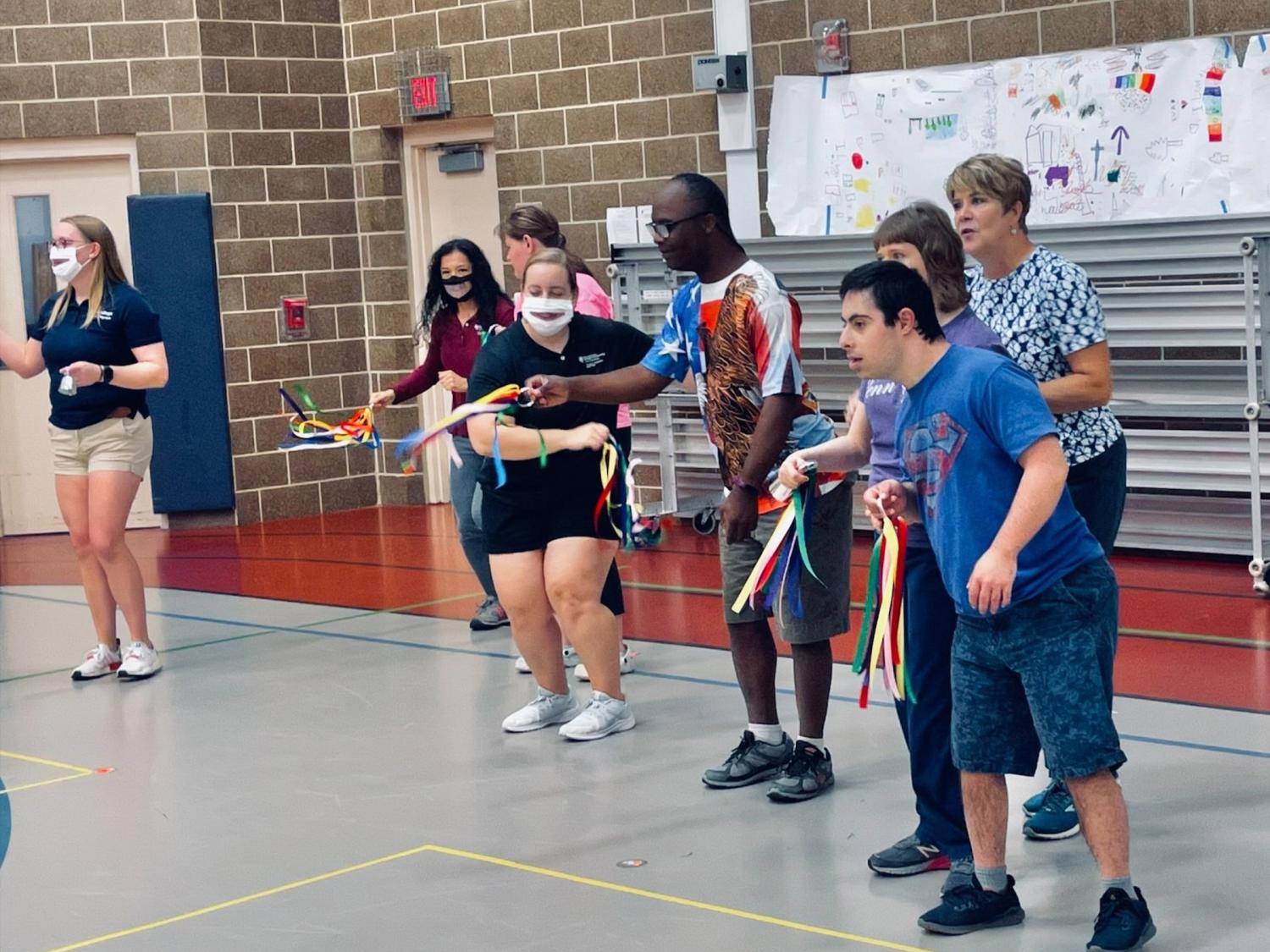 A group of people in a gymnasium dancing with ribbons