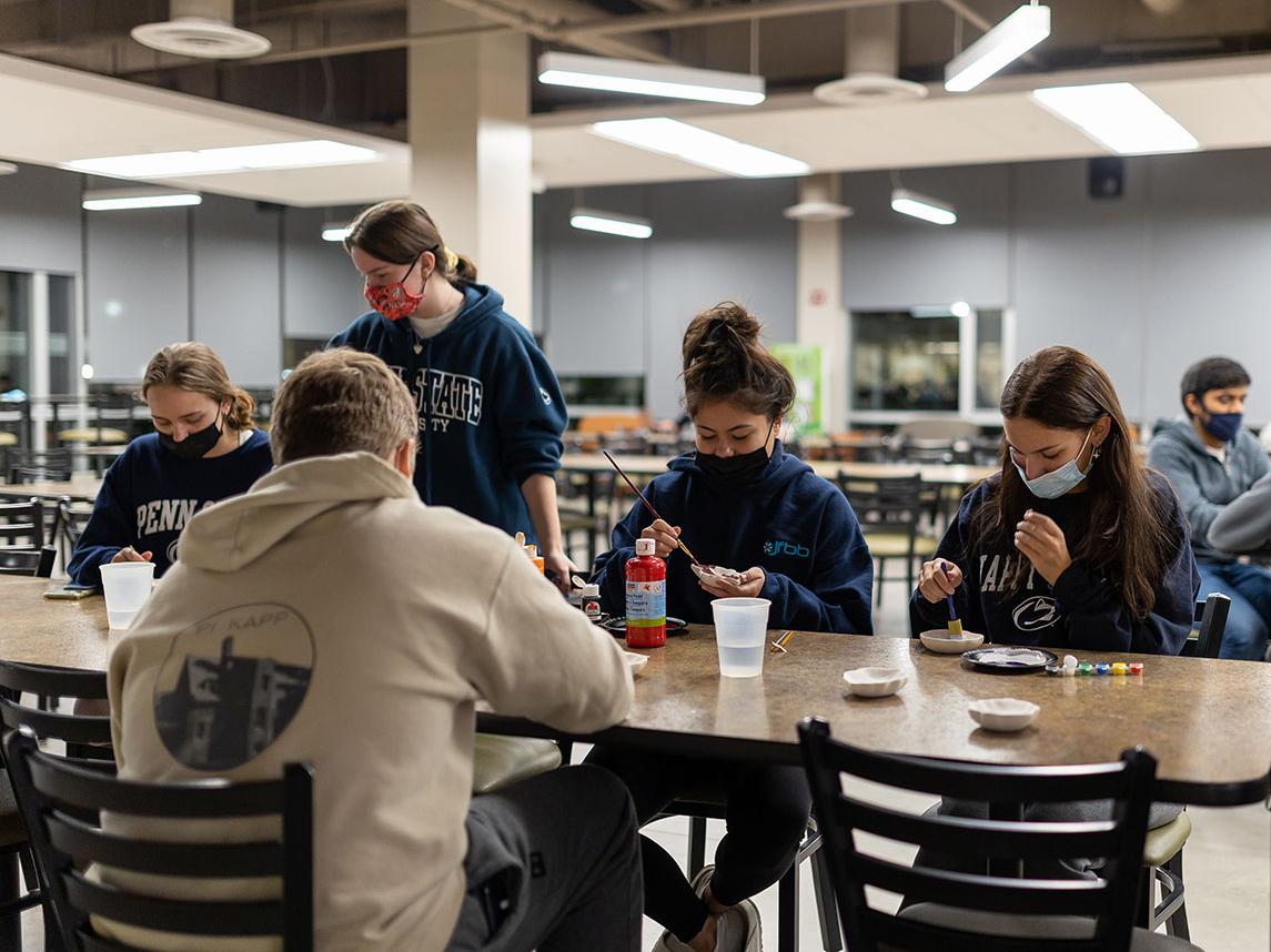 students painting at a table in a common area