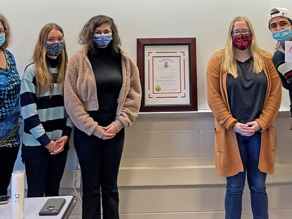 Current and newly inducted members of Lambda Pi Eta pose for a group photo after induction ceremony