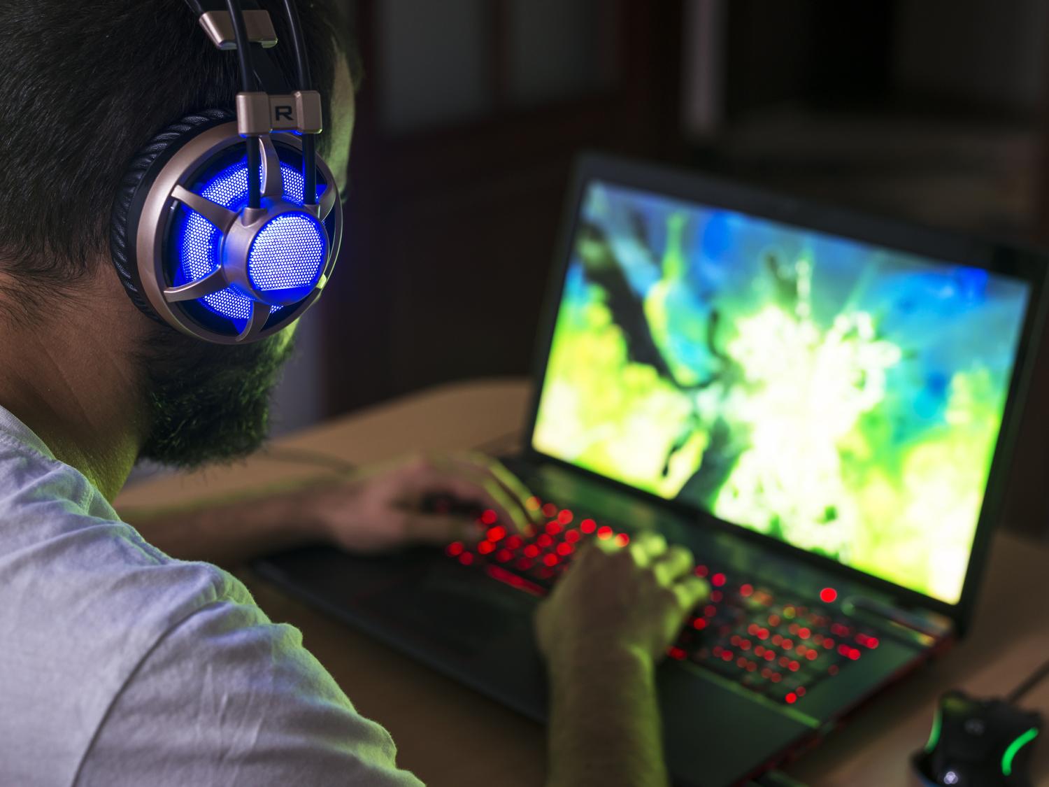 Photo of a gamer wearing headphones and sitting at a desktop computer playing a game