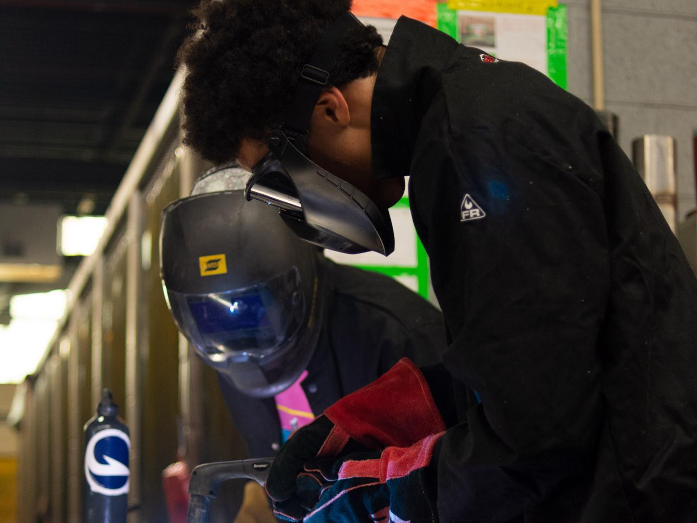 Two people working in a welding lab with a plasma cutter