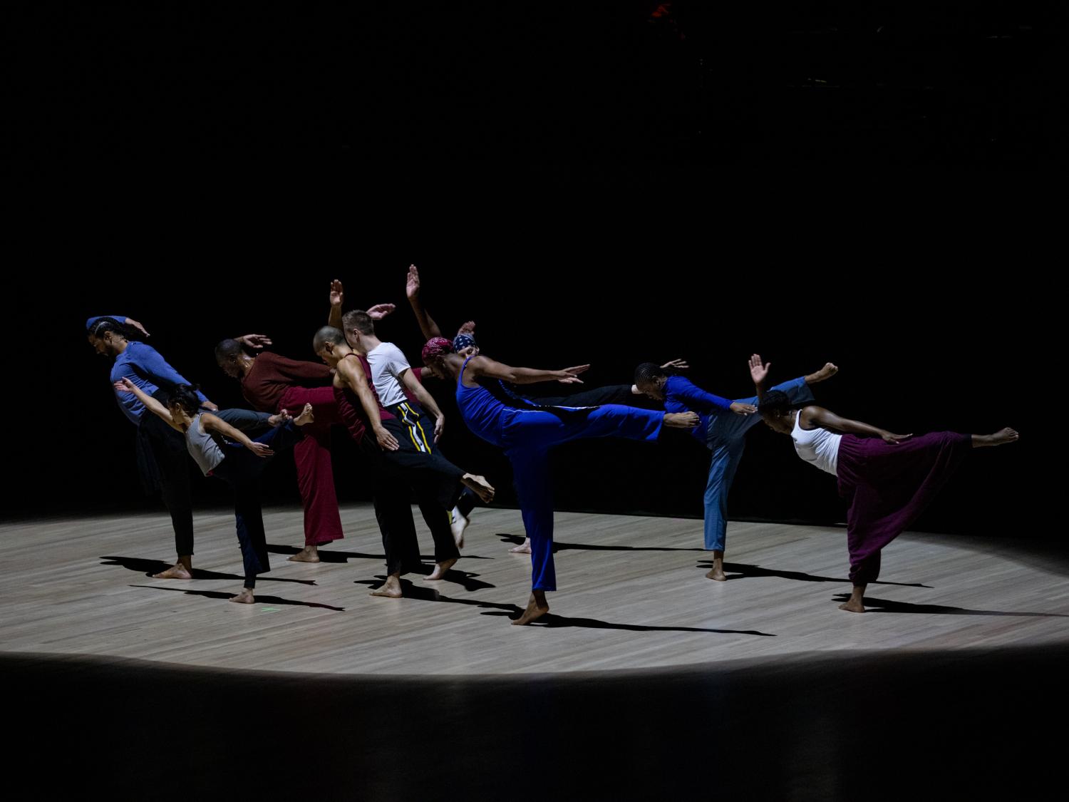 A small group pf dancers each stand on one leg and lean in the same direction.