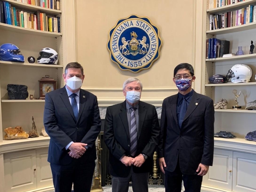 Three men standing next to each other in an official-looking office