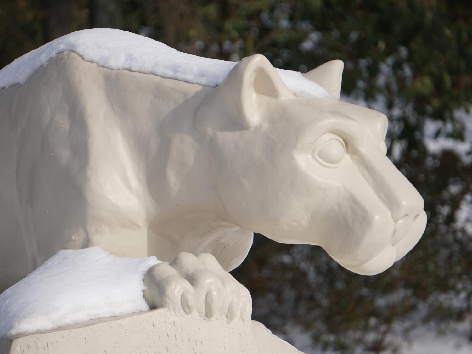 Statue of a lion looking out over snow.