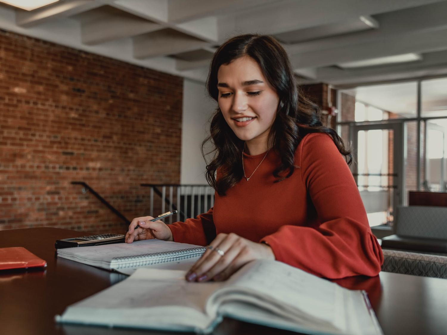 Student sitting at table with books and calculator