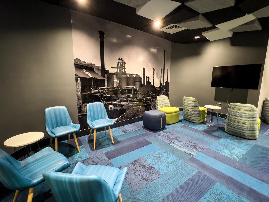 Collaborative space with chairs, tables, and a giant piece of art on the way. 
