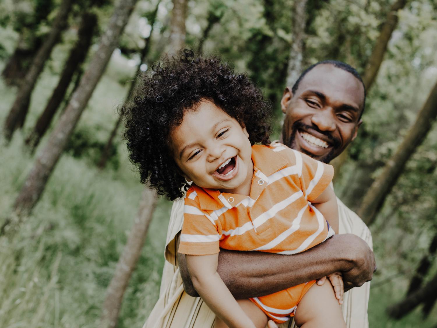 A Black man holding a grinning toddler