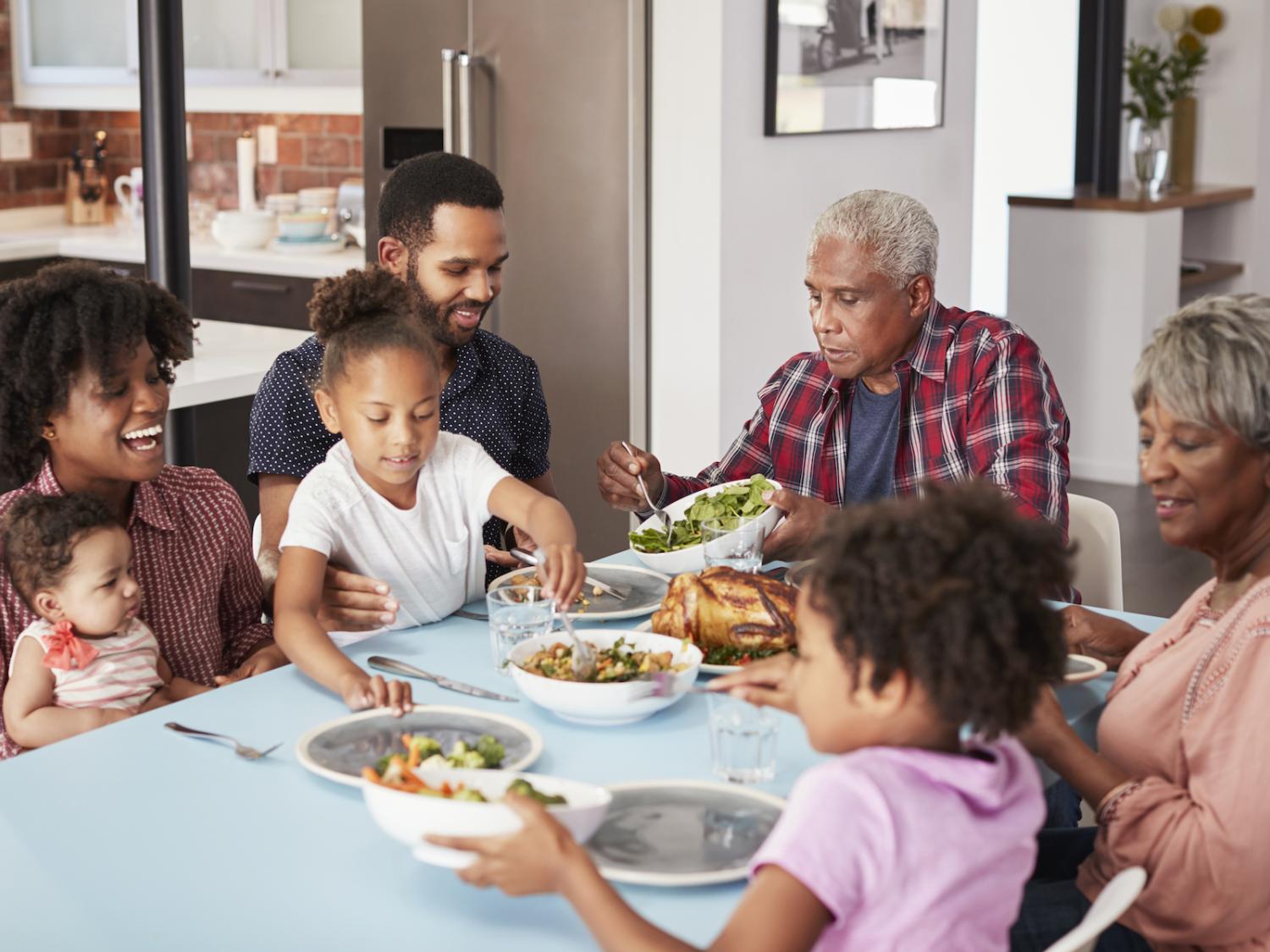 Multi-Generation Family Enjoying Meal Around Table At Home