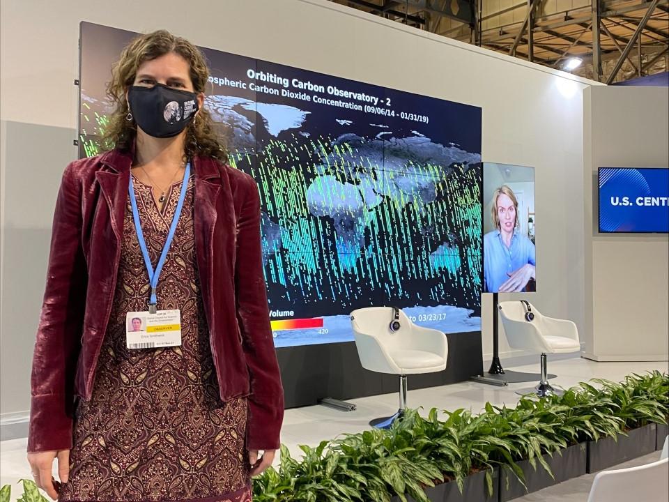 Erica Smithwick standing by a stage and large screen at COP26