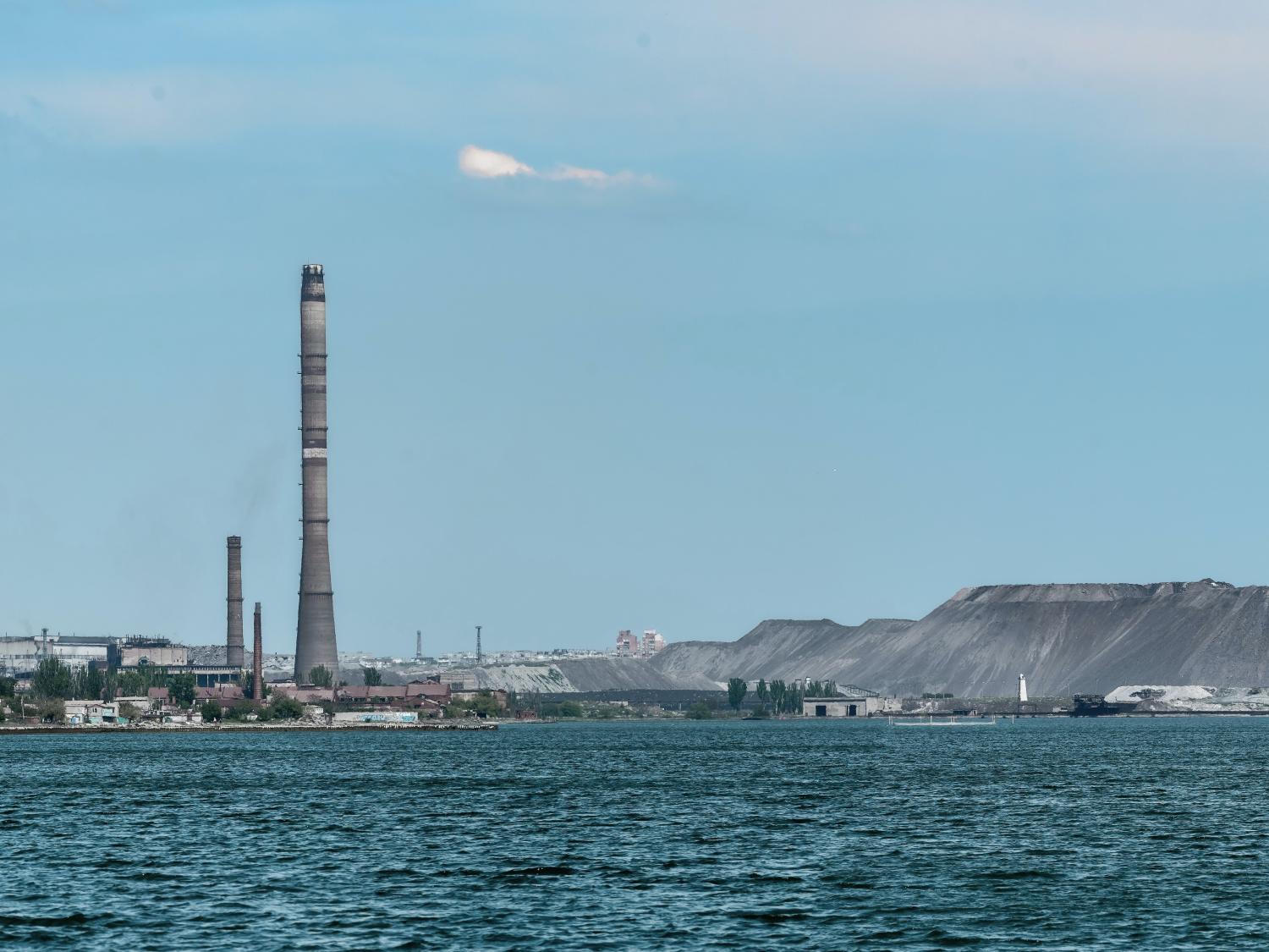 Faraway shot of a factory located near a large body of water