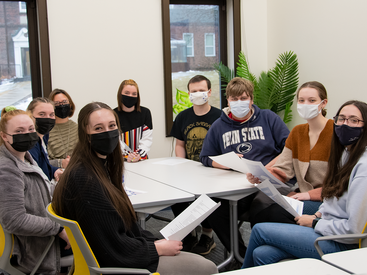 A group of tutors gathers around a work table in the Learning Center.