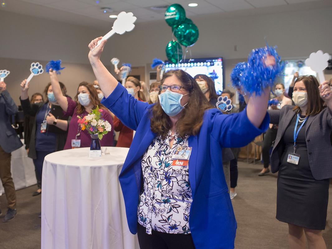 A group celebrates, with arms in the air and holding pom poms