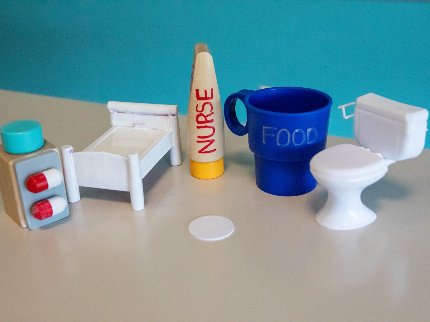 A collection of dollhouse toys represent how NCF technology could be affixed to everyday items to replace the standard call button in pediatric hospital rooms