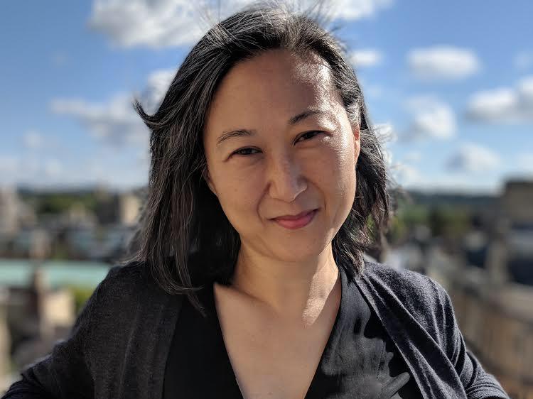 portrait of woman standing outside leaning back on a railing 
