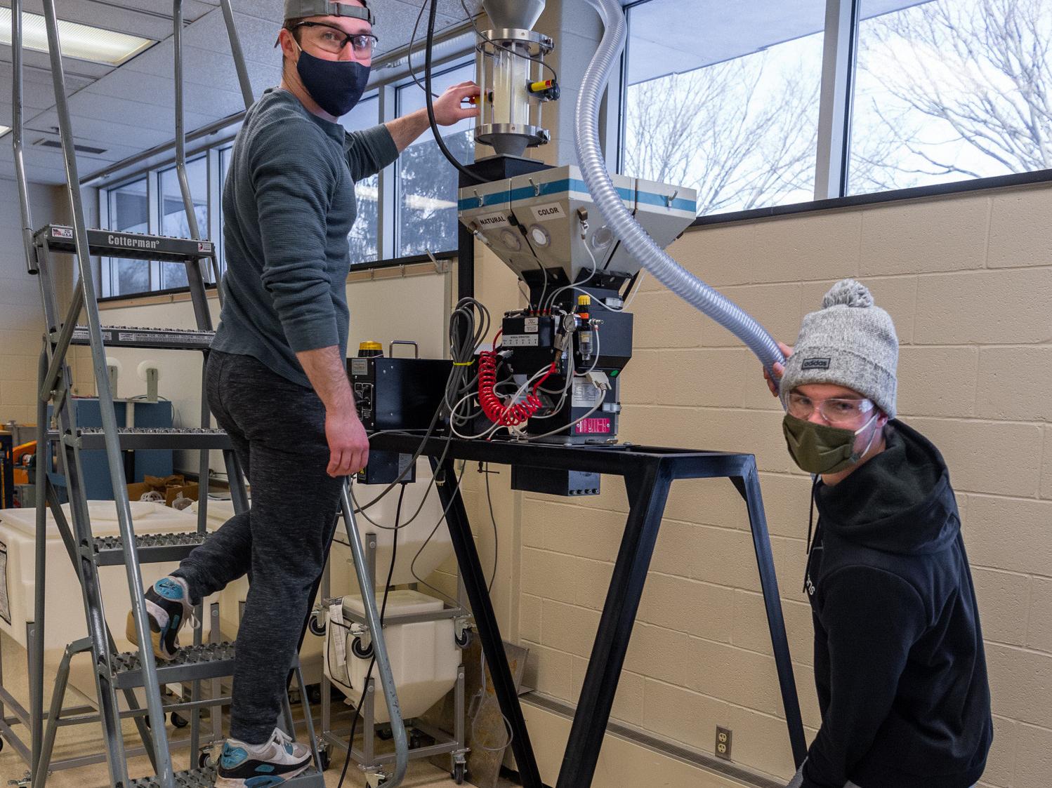 Two Penn College plastics students work with Novatec equipment.