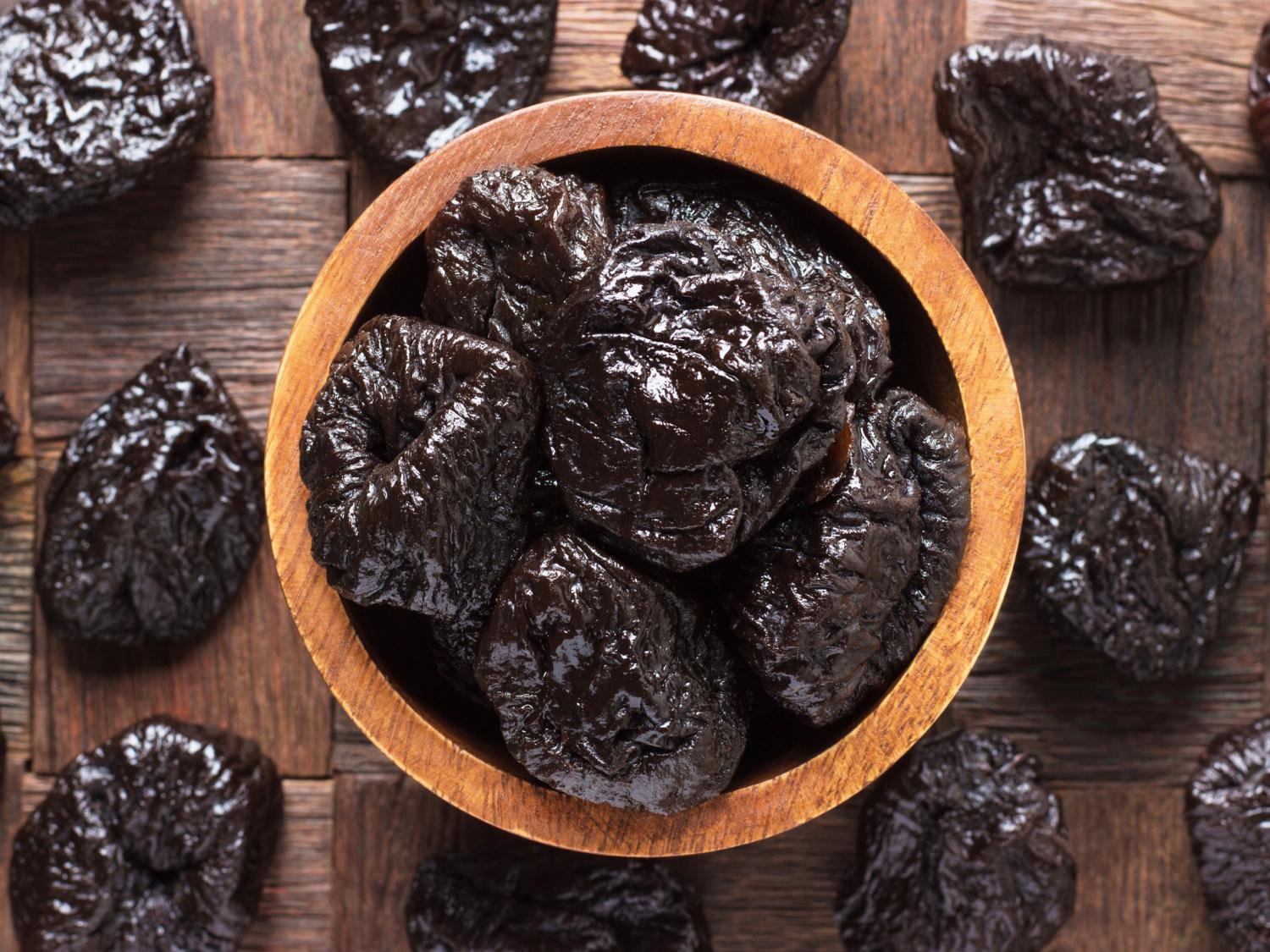 A bowl of prunes sitting on a table