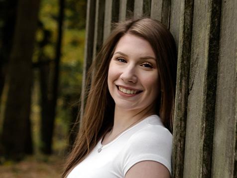 Student learning up against fence outdoors.