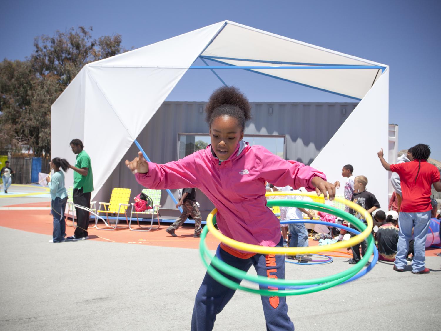 A little girl hula hooping in a community park. 