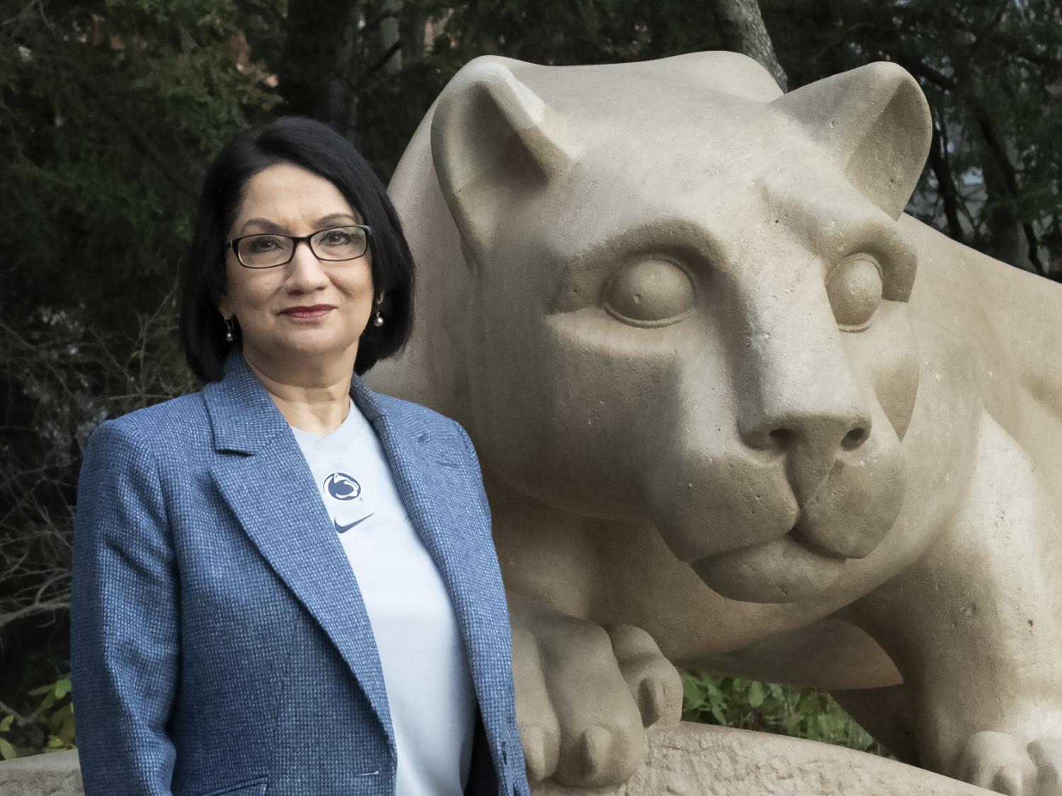 Neeli Bendapudi stands in front of stone Lion Shrine statue at Penn State.