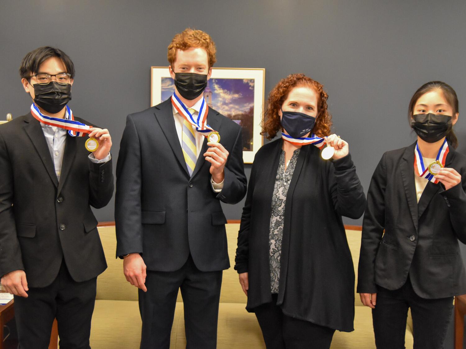Thee young men and one women, professionally dress,  hold first-place medallions