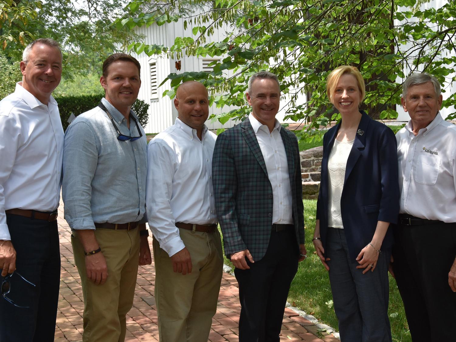 A group of people wering professional attire pose for a photo outside.