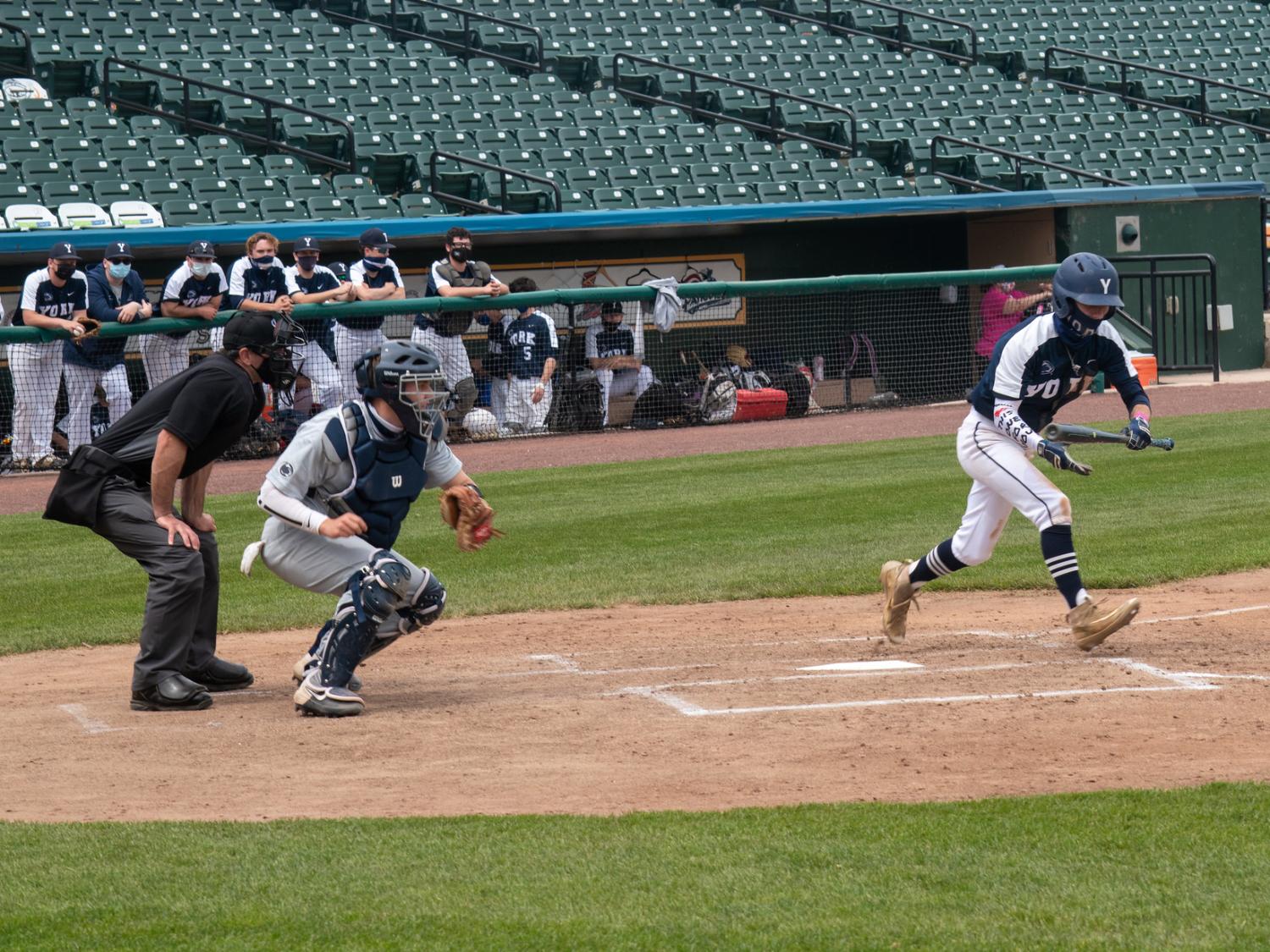 Baeball player swinging bat, catcher and umpire at stadium