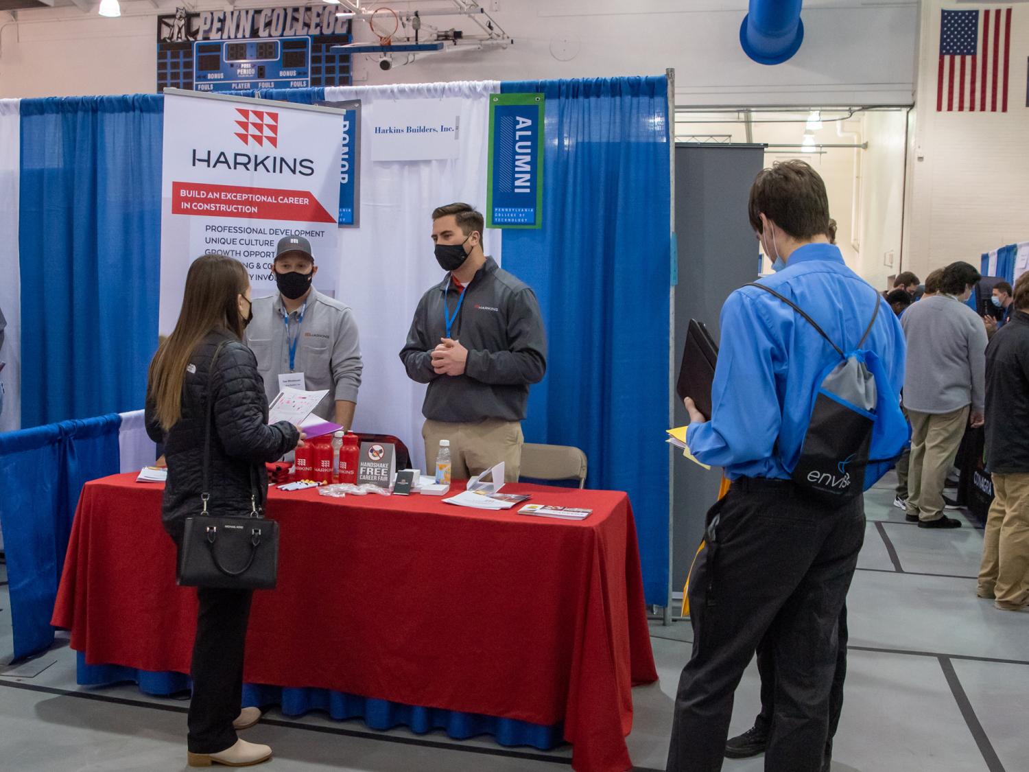 Several people gather around an information table at a career fair.