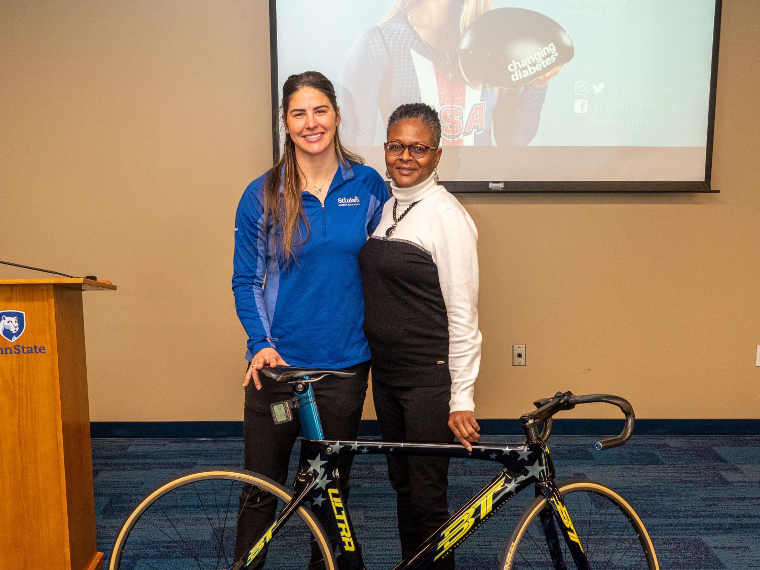 Mandy Marquardt and Tina Richardson stand next to bike. 