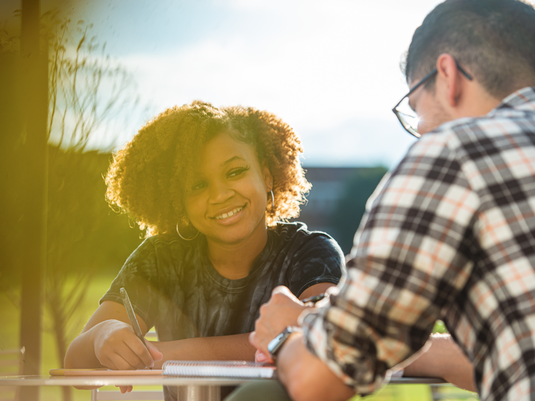Two students share a. table outside on campus