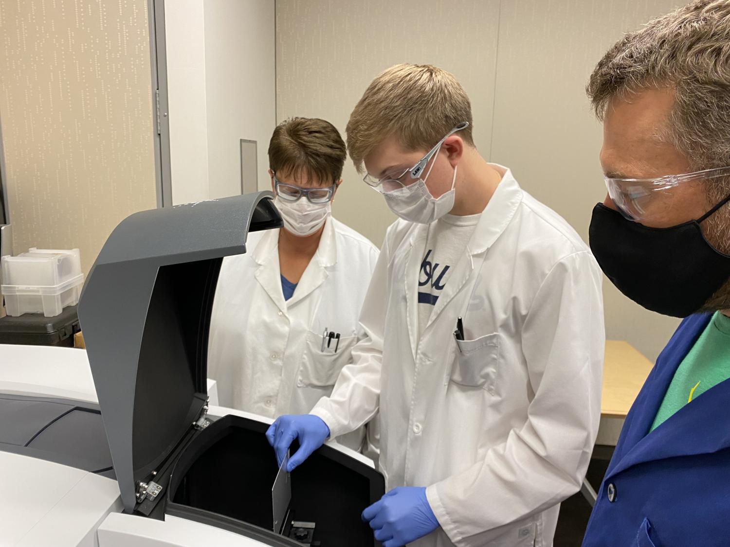 Three people loading a sample into a lab machine