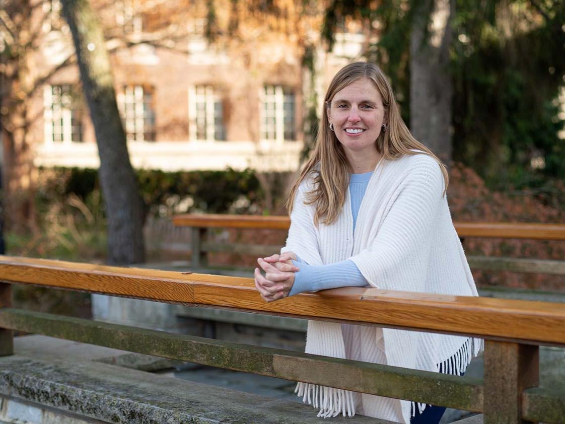A woman stands with her arms bents on the railing of a bridge. 