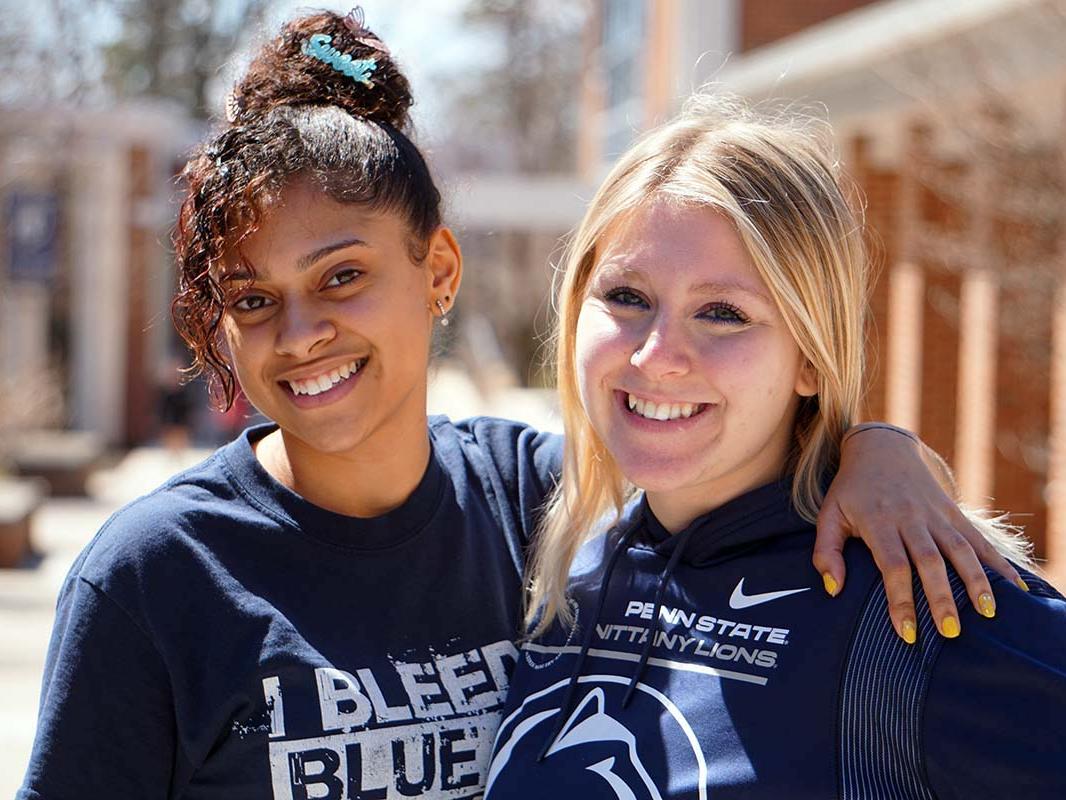 Two female students smiling on a college campus.