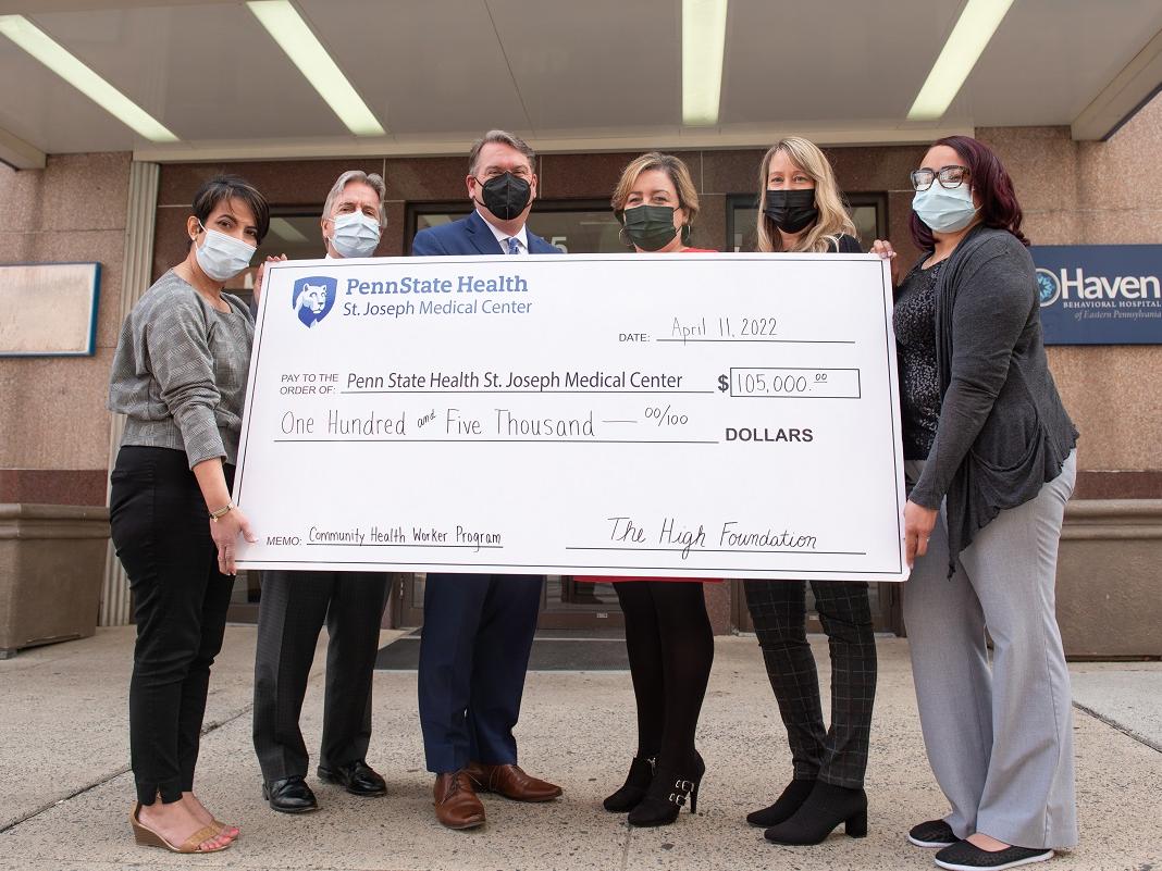 Six people pose with an oversized check in front of a building. The check, in the amount of $105,000, is from the High Foundation and made payable to Penn State Health St. Joseph Medical Center.