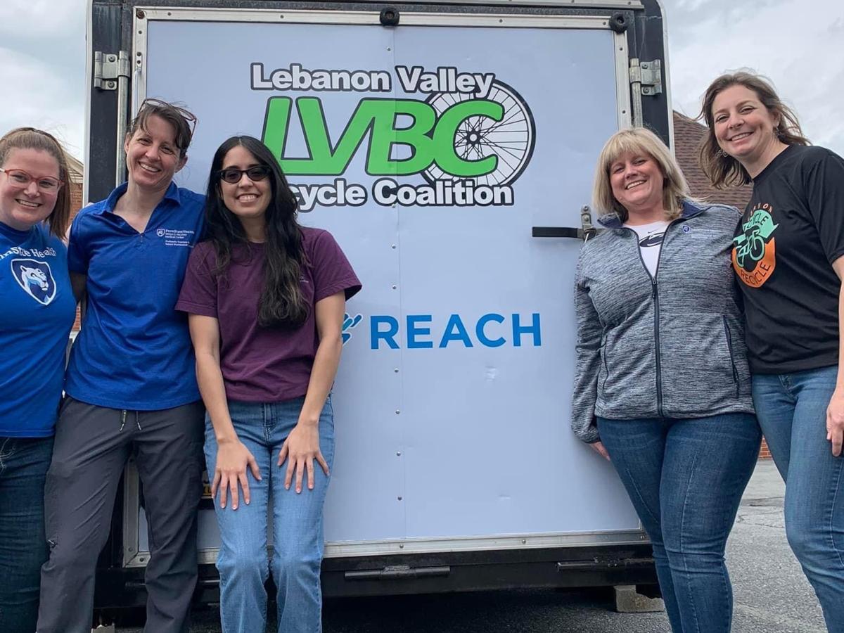 Five women pose in front of a trailer bearing the “Lebanon Valley Bicycle Coalition” and Penn State REACH logos.
