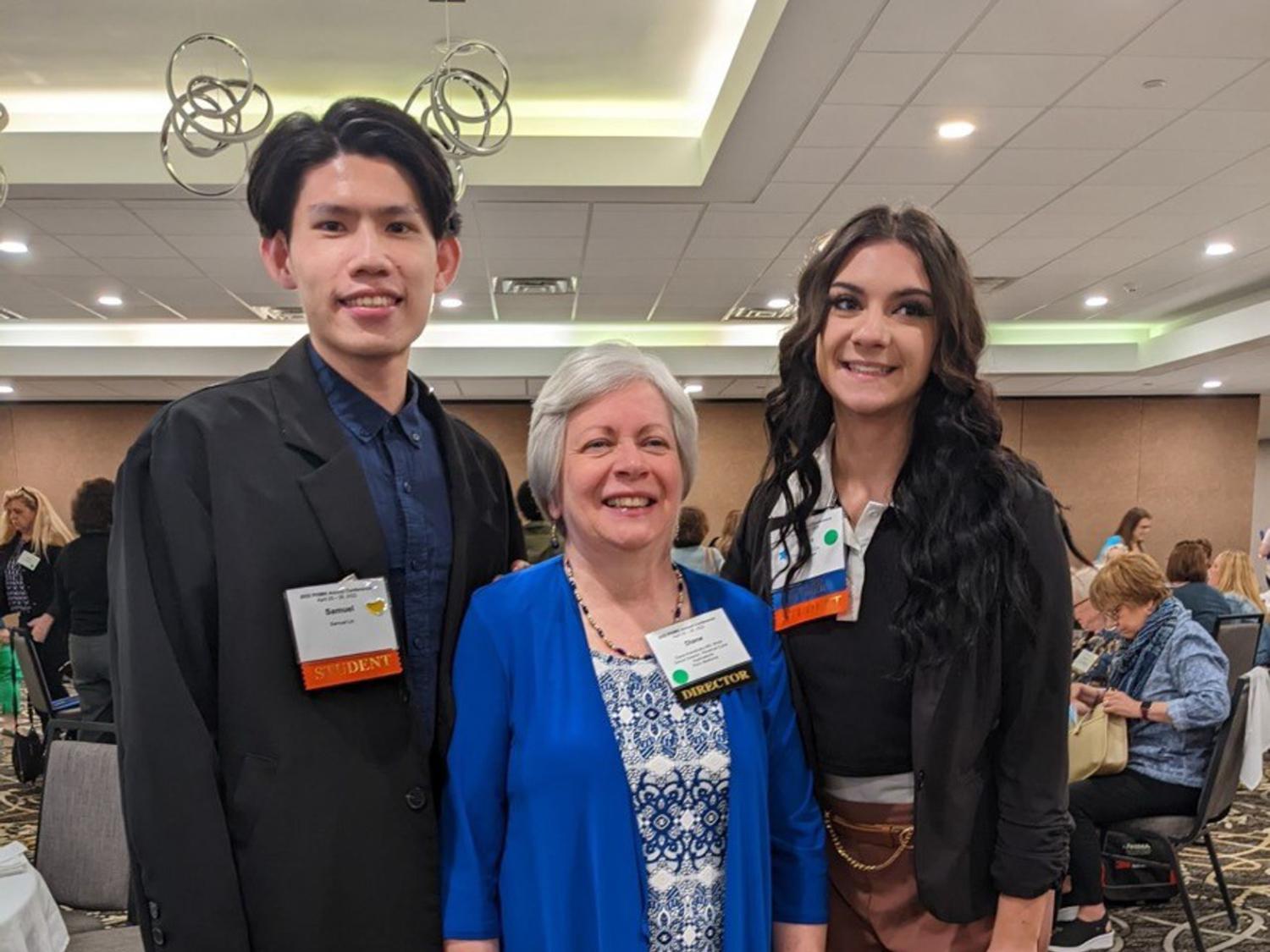 Three people pose for a photograph at a conference