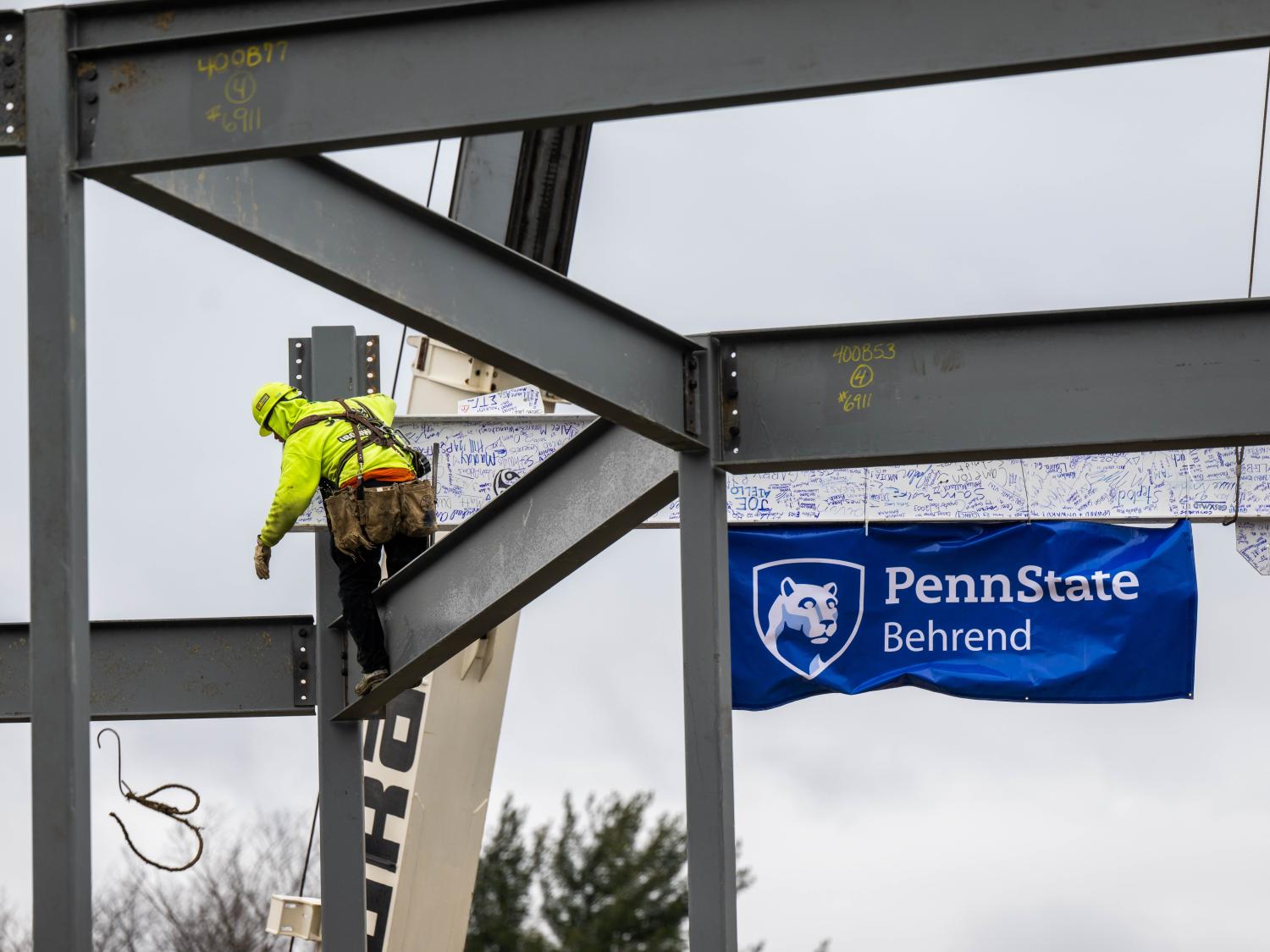 A steelworker helps set a 32-foot beam while building Penn State Behrend's new Erie Hall.
