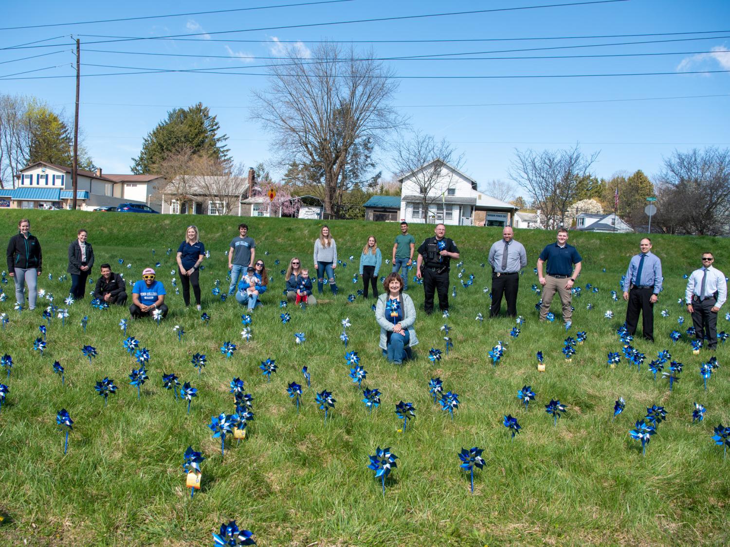 Pinwheels planted in a field with people looking on