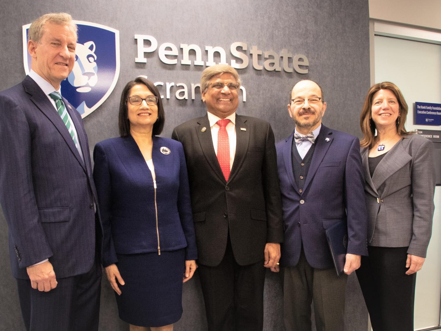 group of PSU officials and special guests posing for a photo in front of Penn State wall