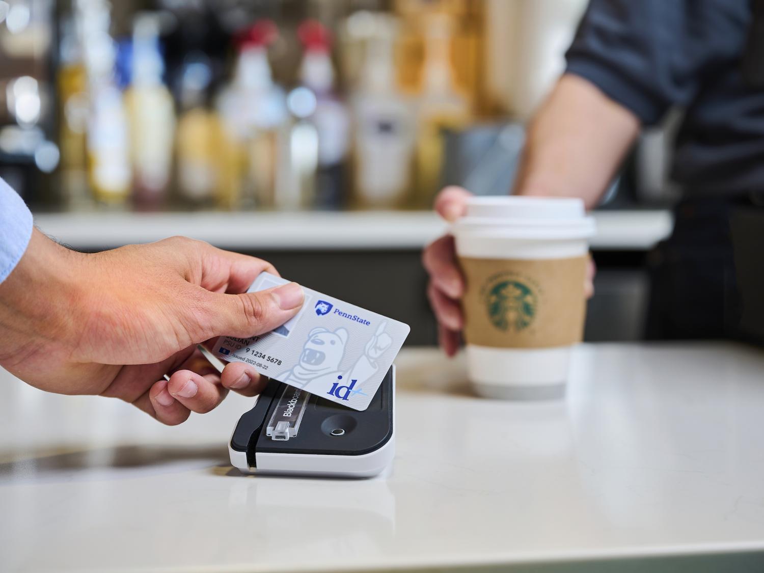 Student taps new id+ card to payment reader with coffee cup in background