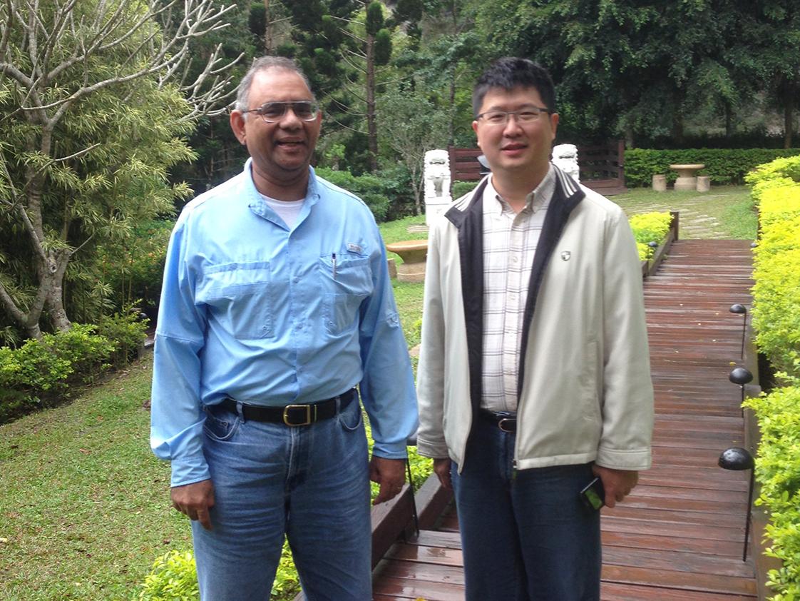 Two men stand together in a park. 