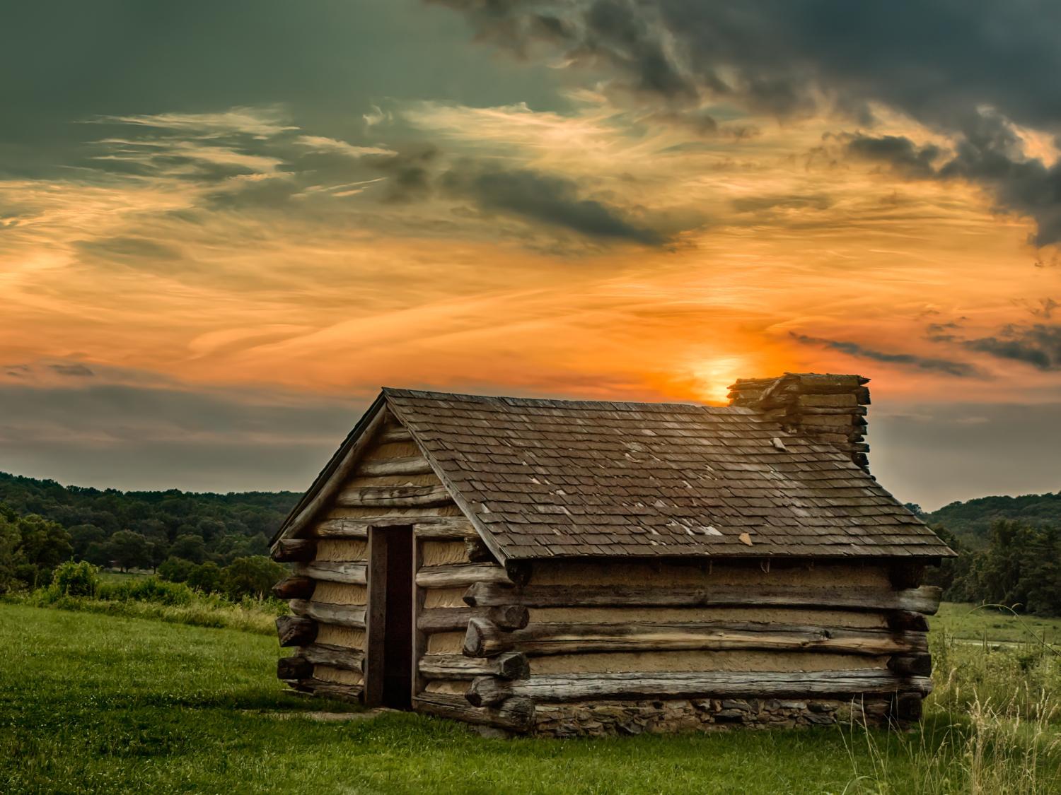 Sun setting over a wood cabin