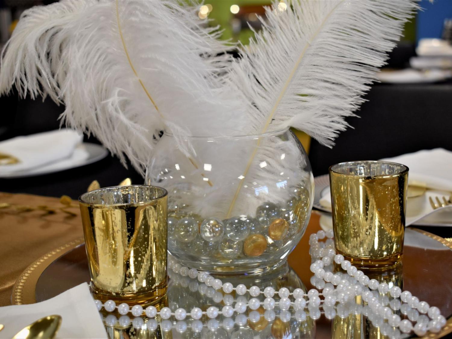 Centerpiece at old Hollywood event with feathers, candles, and pearls