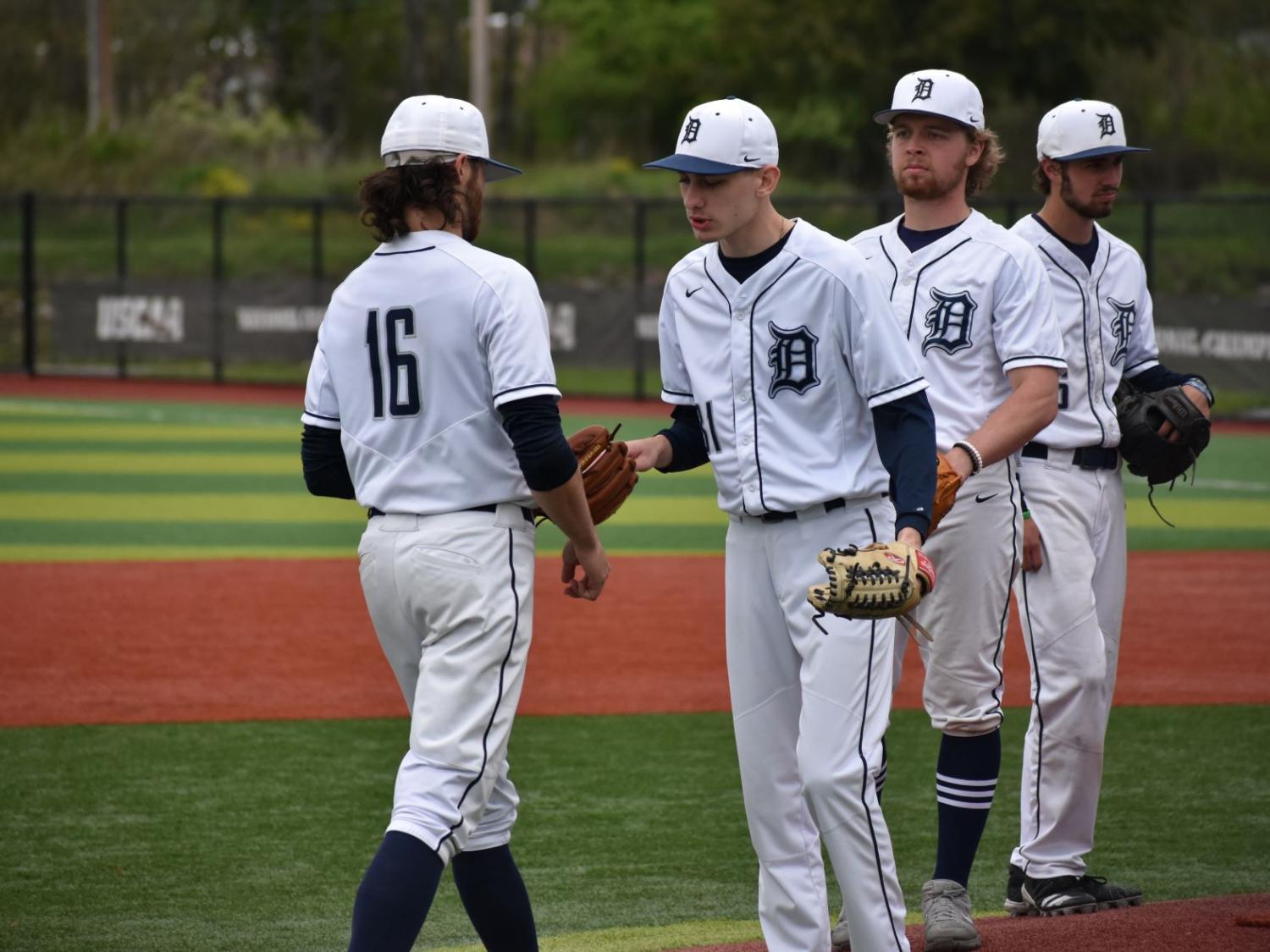 Pitching change in a baseball game, exiting pitcher hands ball to incoming pitcher