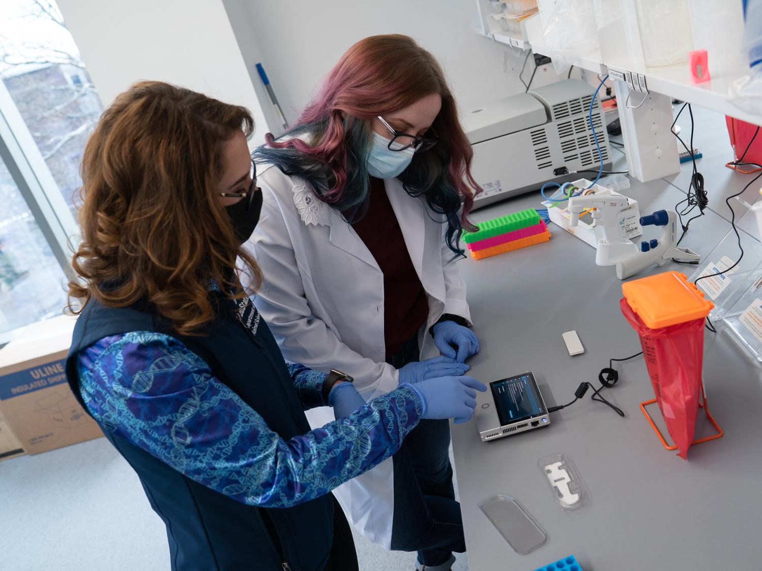 Assistant Professor of Food Animal Microbiomes Erika Ganda and graduate student Emily Van Syoc working at a lab bench