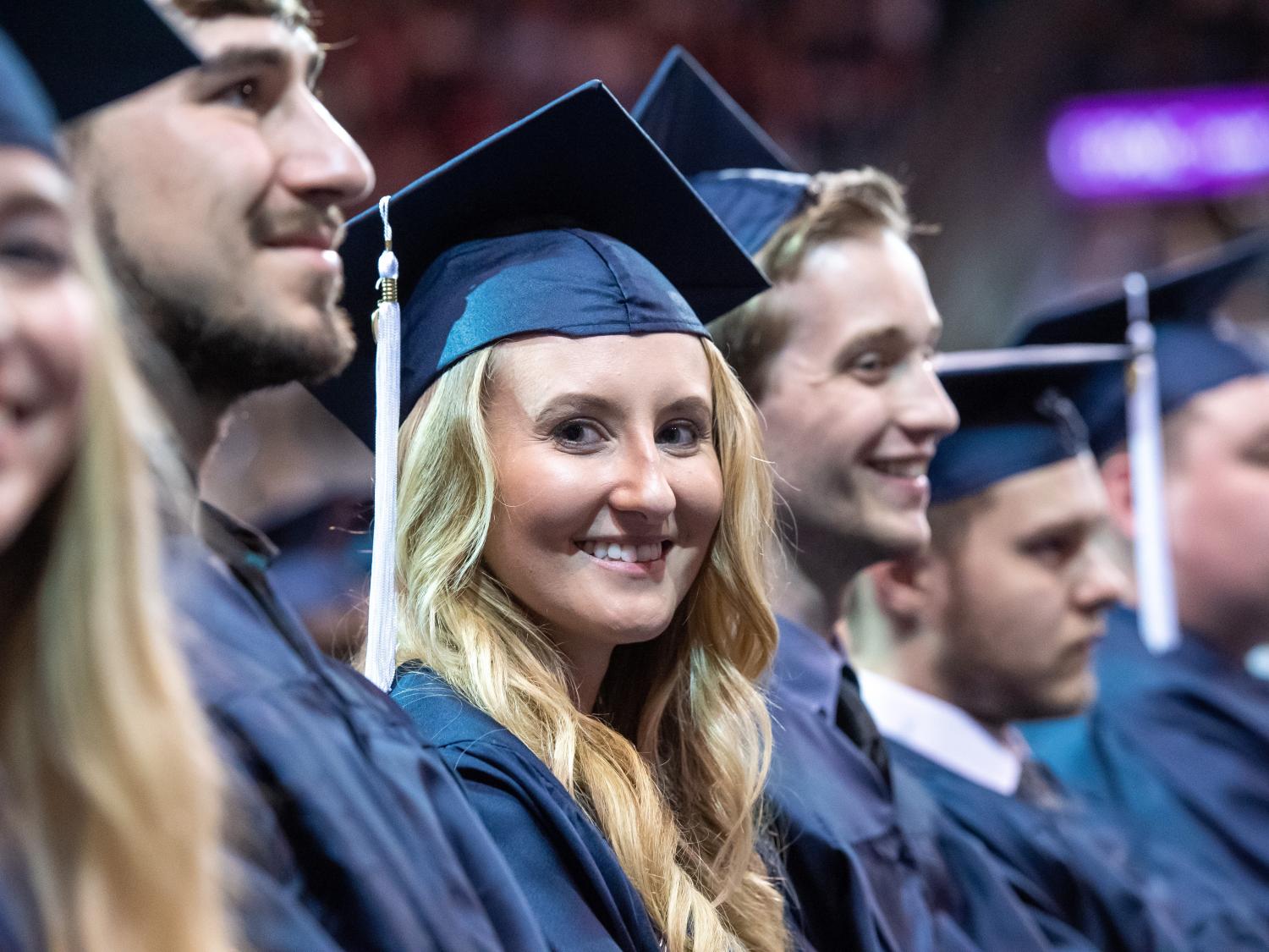 New graduates smile during a Penn State Behrend commencement program.
