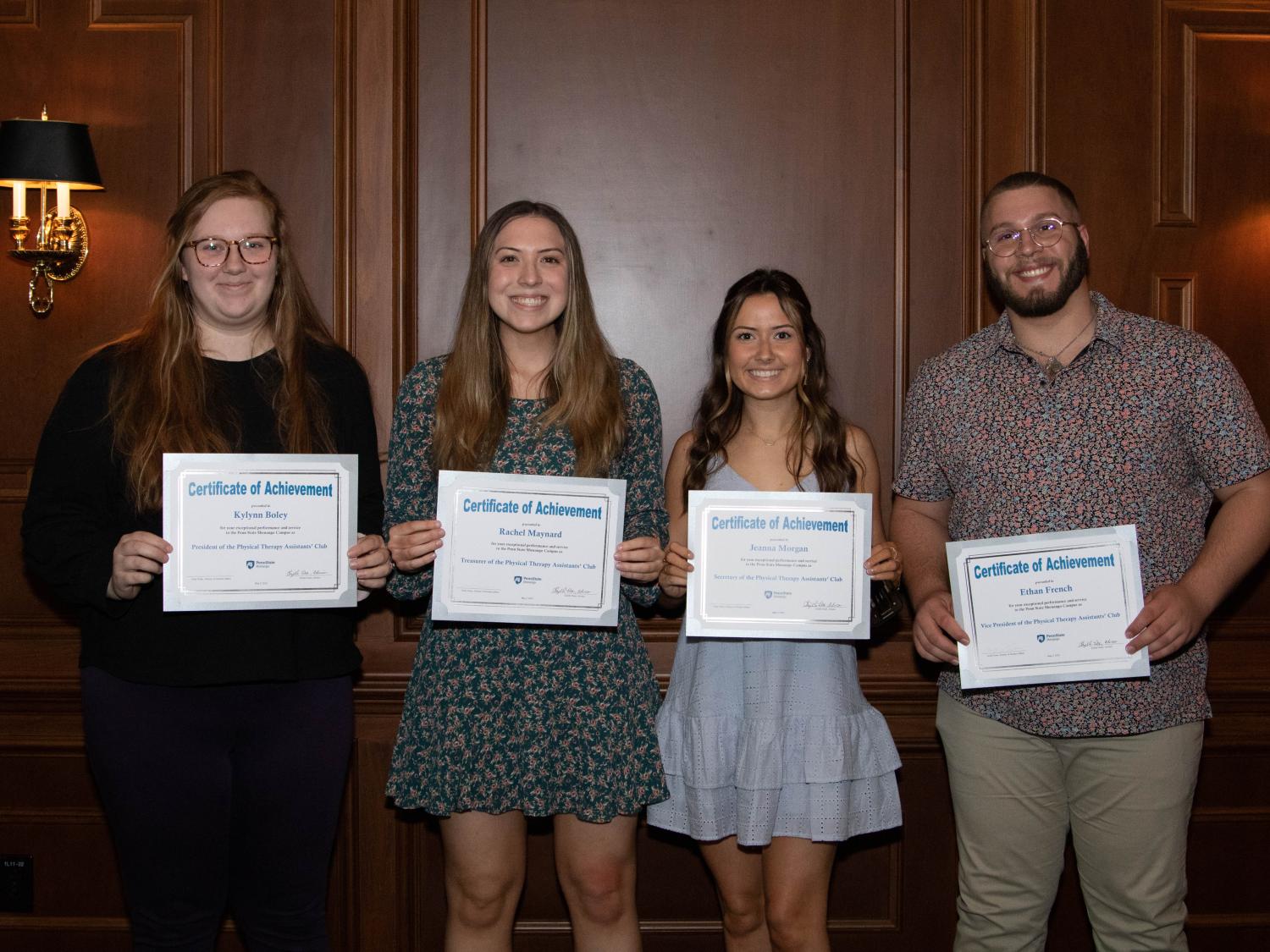four students hold paper certificates