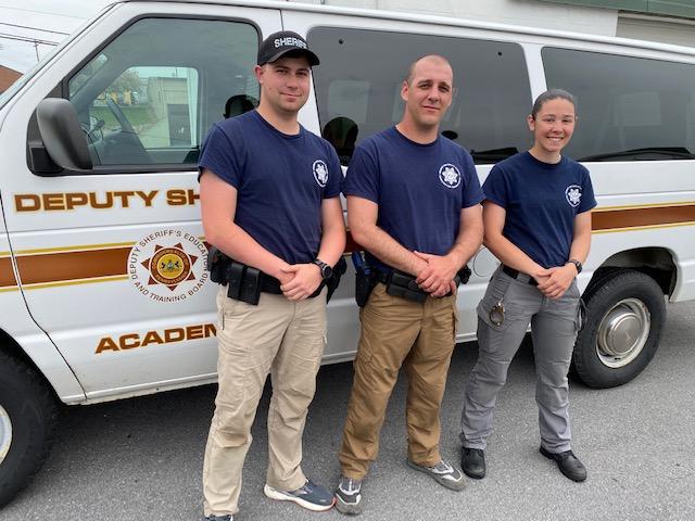 Three deputy sheriffs in front of sheriff's training program vehicle