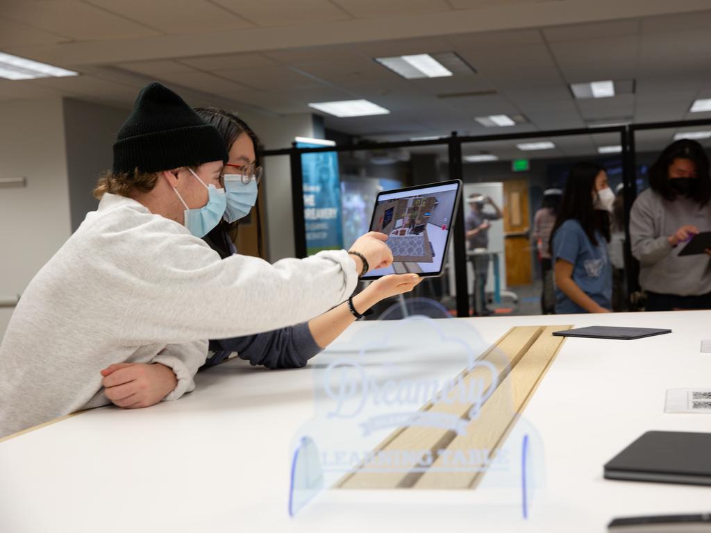 Two students experience augmented reality through an iPad at the Dreamery.