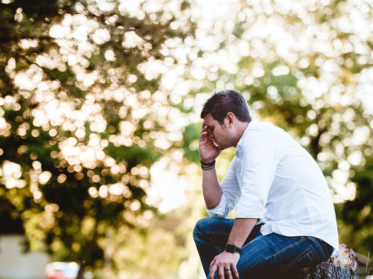 Man sitting with his face in his hand looking depressed
